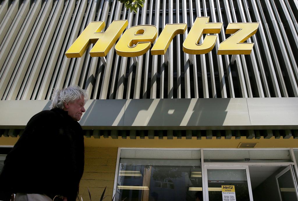 A person walks by a Hertz rental car office in San Francisco, 