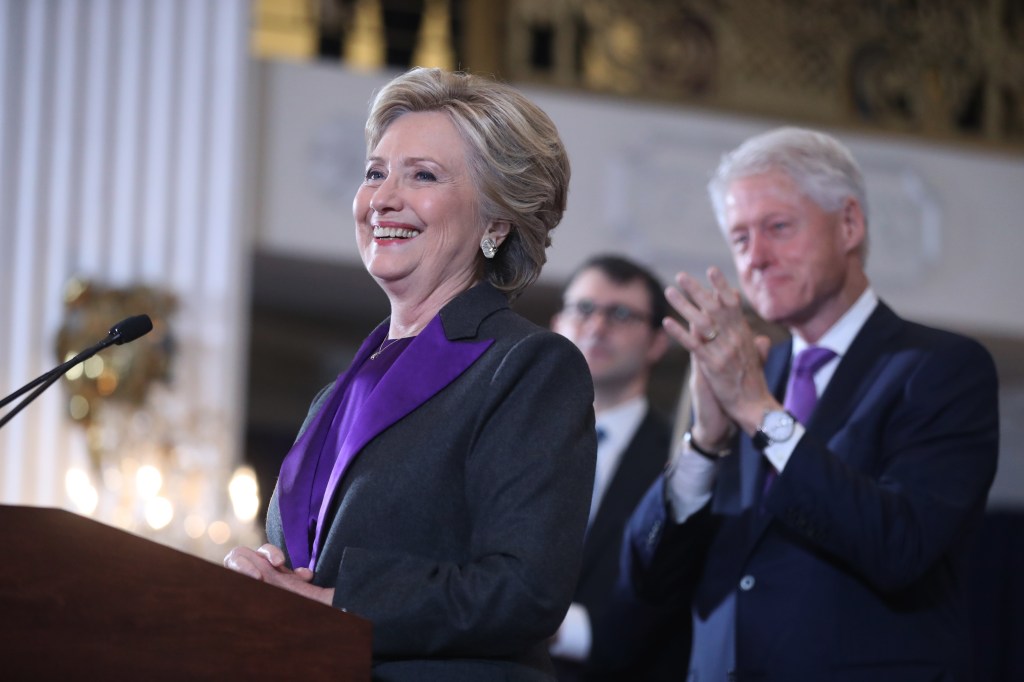 Hillary Clinton at a podium in front of her husand Bill Clinton.