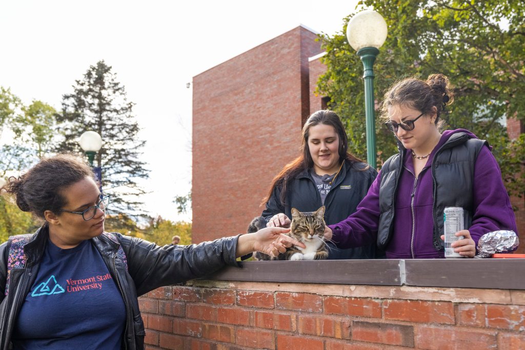 Students at Vermont State University petting Max the Cat, an honorary Doctor of Litter-ature, in front of Leavenworth Hall