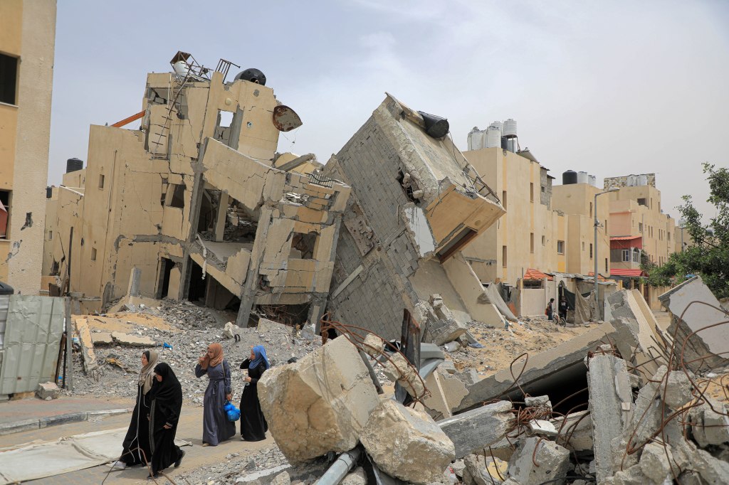 People walking past destroyed buildings in Rafah on May 10, 2024.