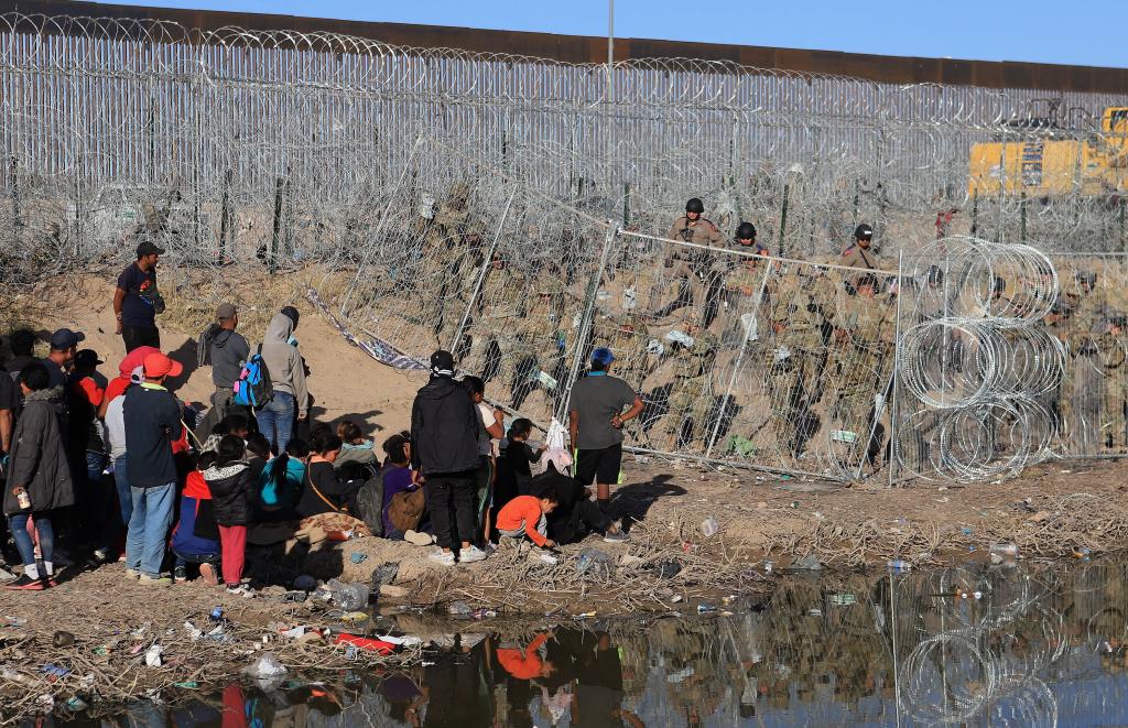 US National Guard personnel reinforce a fence covered in concertina wire in the vicinity of migrants on the border with Mexico, as seen from Ciudad Juarez, Chihuahua, Mexico, 23 March 2024.