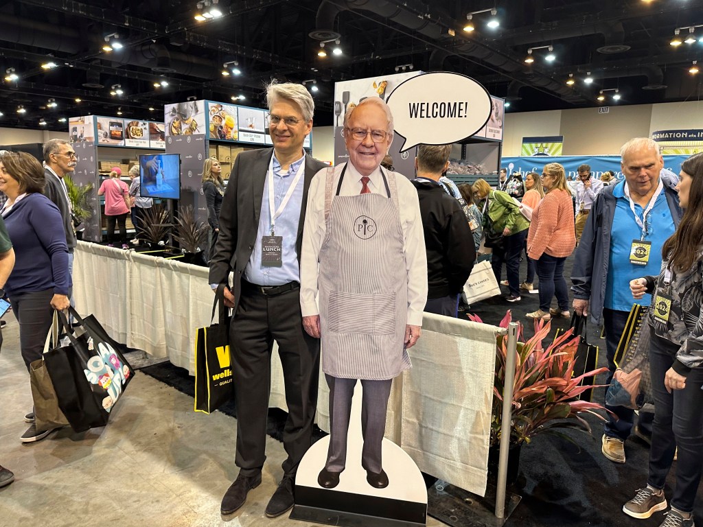 A shareholder taking a picture with a Buffett cutout poster.