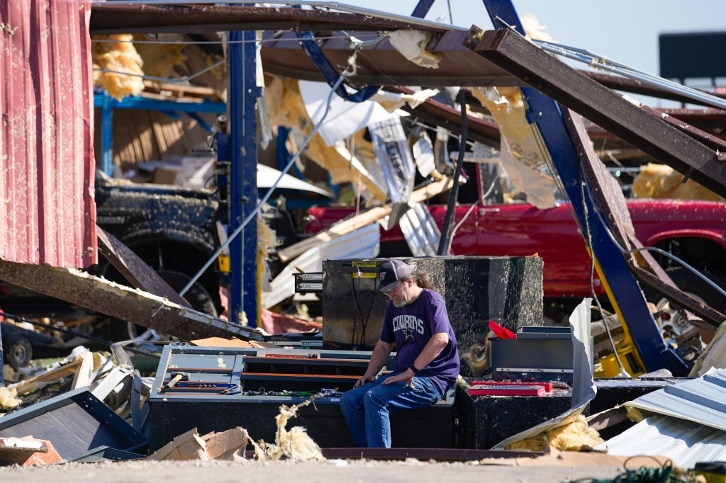 A body shop employee collecting missing tools after the shop was hit by a tornado in Valley View.