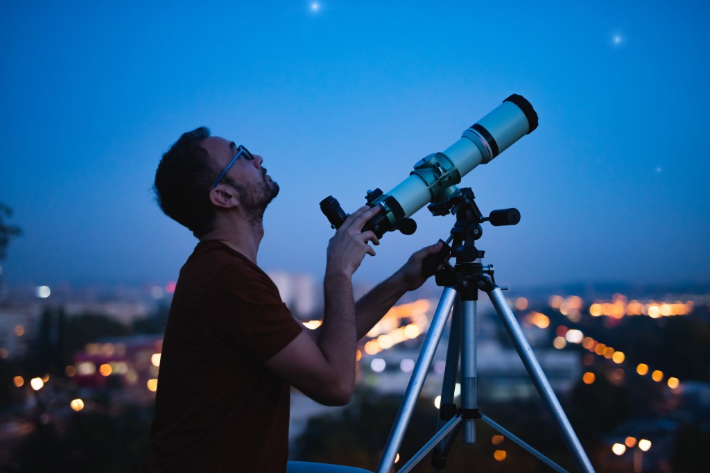 Astronomer with a telescope watching at the stars and Moon with