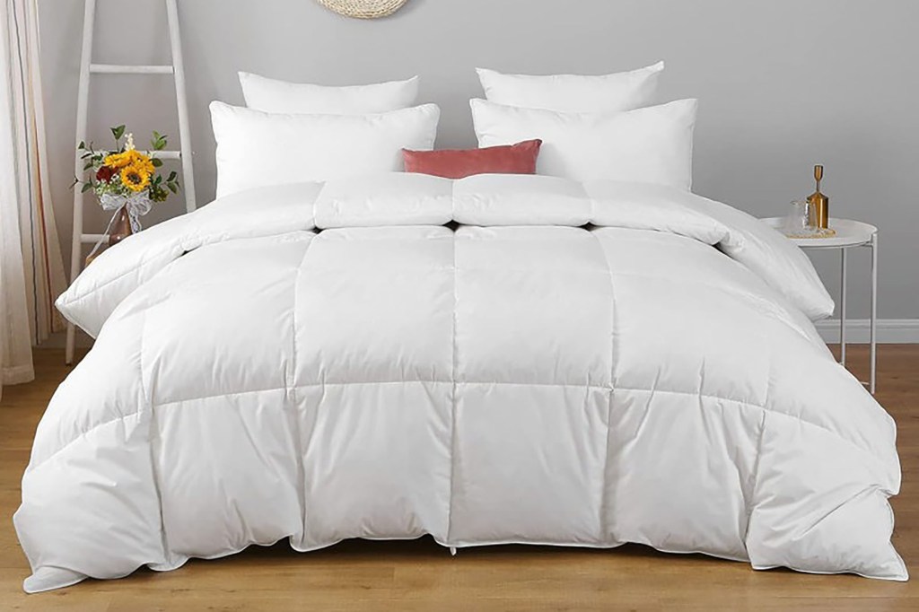 A bed made up with a white all-season feather down comforter and pillows