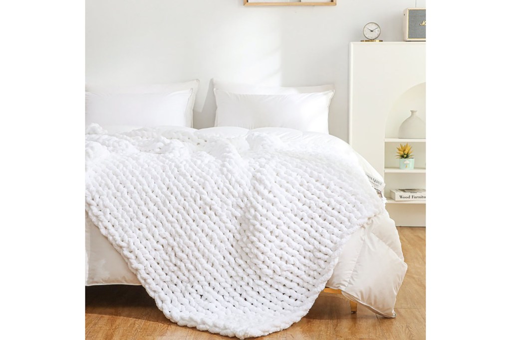 A bed adorned with white blankets and pillows featuring a luxurious Chenille Chunky Knit Throw