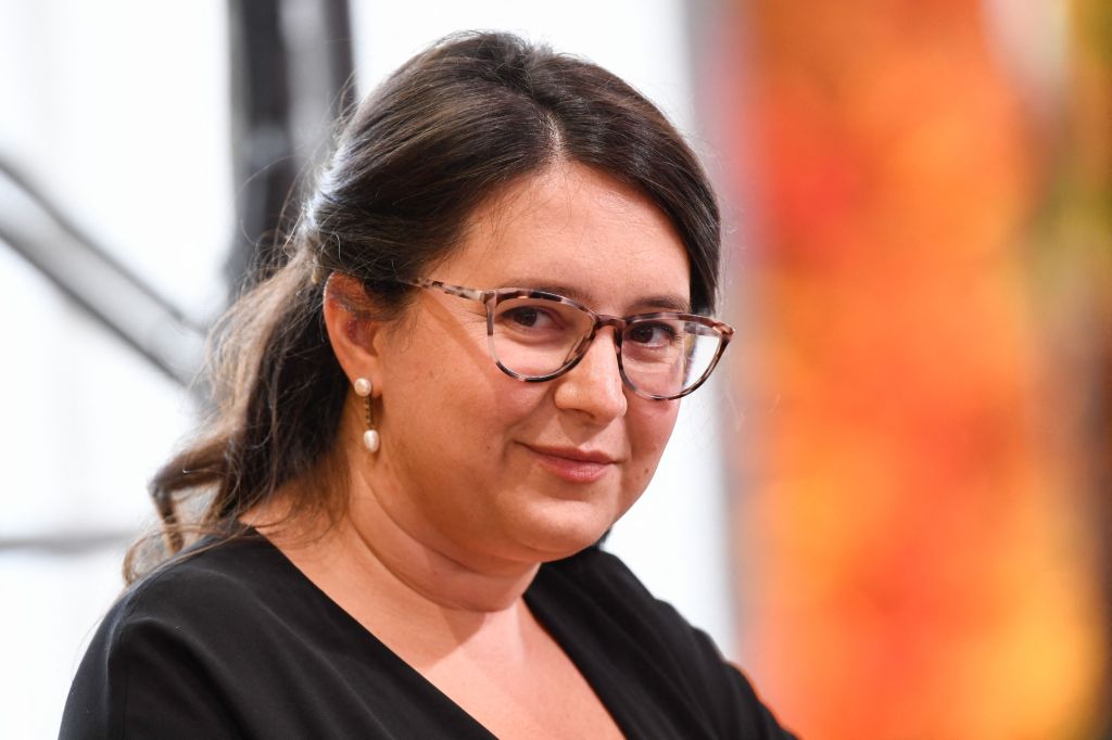 Bari Weiss, Editor of Common Sense, speaking at the Milken Institute Global Conference, wearing glasses and a black shirt