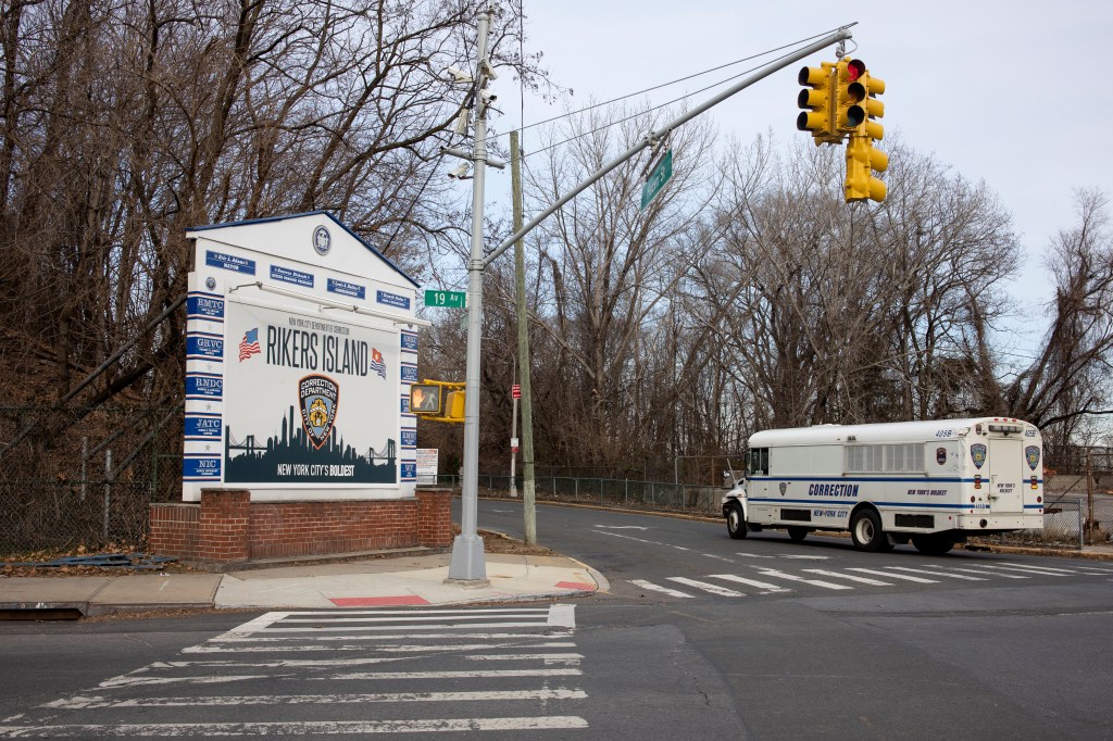 A Department of Corrections bus, used to transport prisoners, drives up to the entrance of the bridge that connects to Rikers Island, January 15, 2022 in Queens, New York