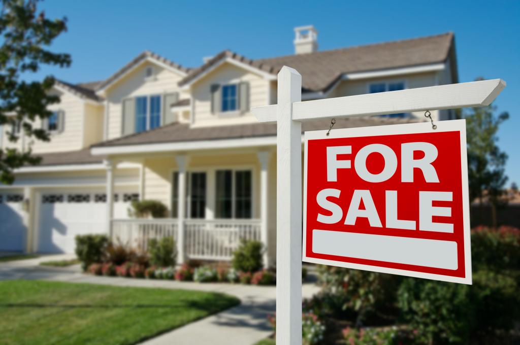 A home for sale sign posted in front of a new house