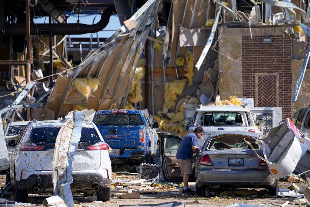 Hugo Parra, of Farmers Branch, Texas, collecting his belongings from his destroyed car after taking shelter from the tornado in a truck stop.