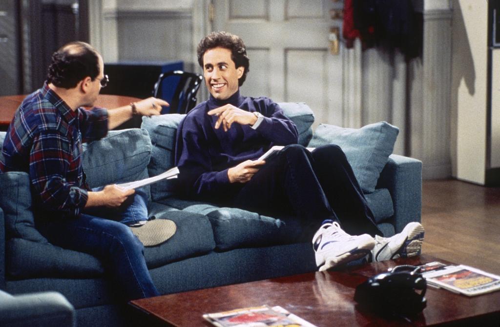 Jerry Seinfeld sits on his couch opposite Jason Alexander on the set of "Seinfeld."