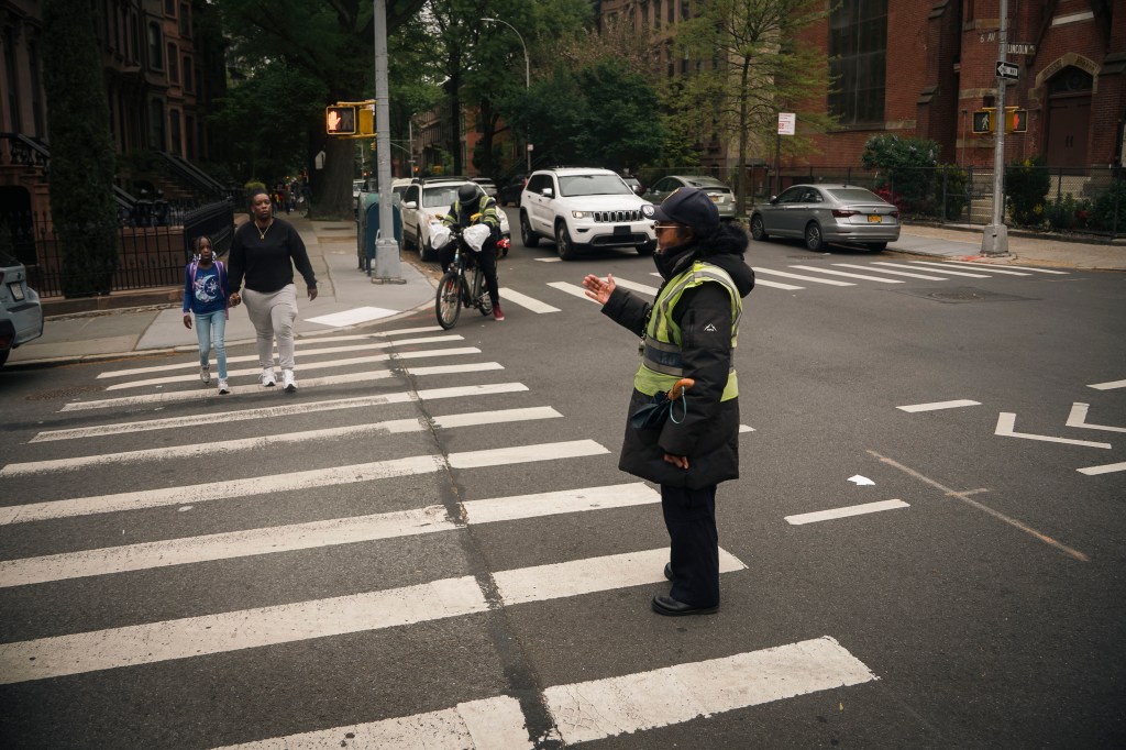 Maggie Poston standing in profile in a Park Slope crosswalk, urging people to cross. 