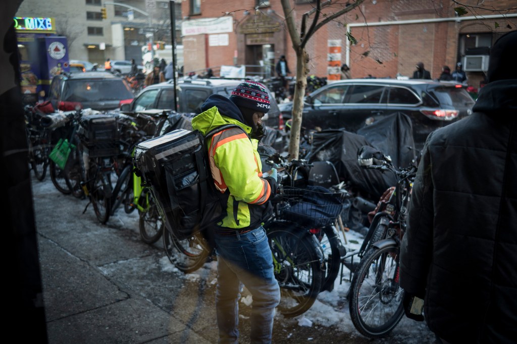 Food delivery bikes and a worker on the sidewalk.