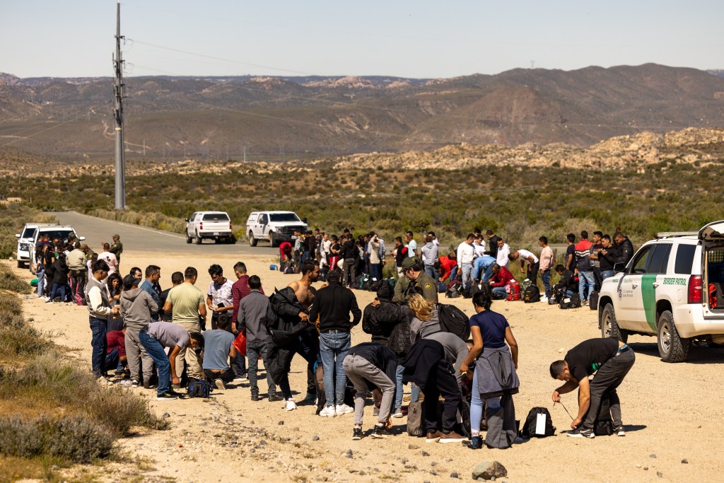 Migrants walk around the border fence and into the United States in Jacumba Hot Springs, where they are detained by Border Patrol and prepared for processed for immigration intake.