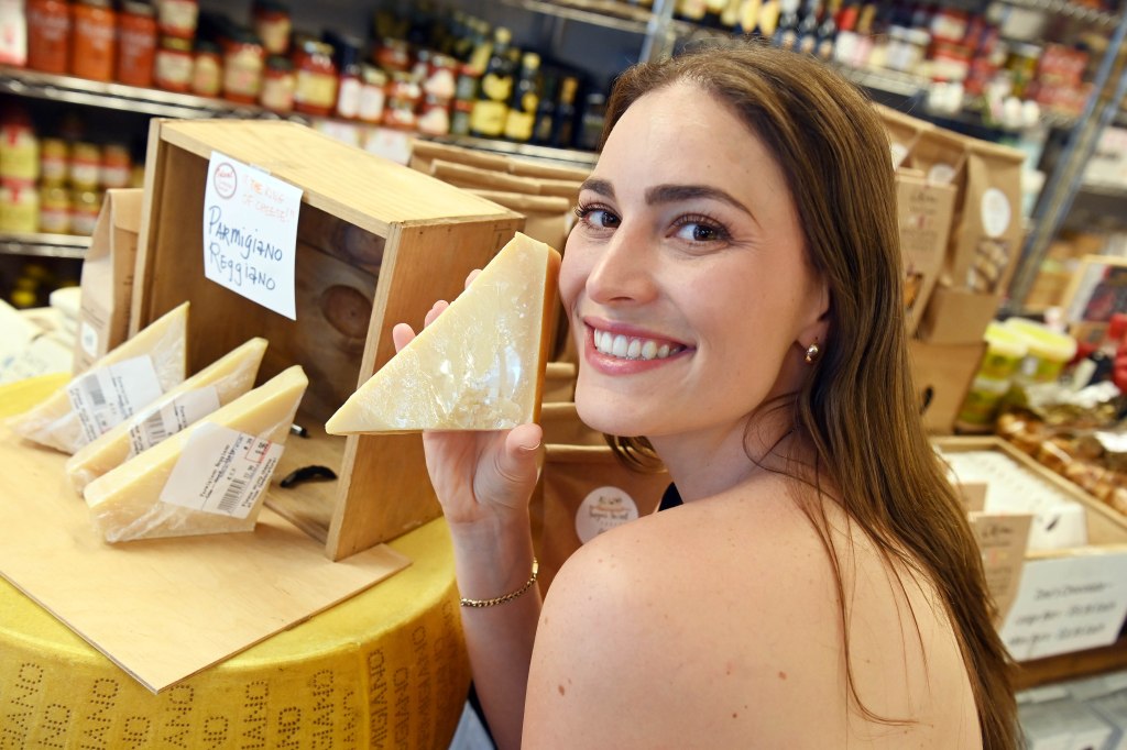 Adela Cojab holding up a triangle of Parmesan cheese