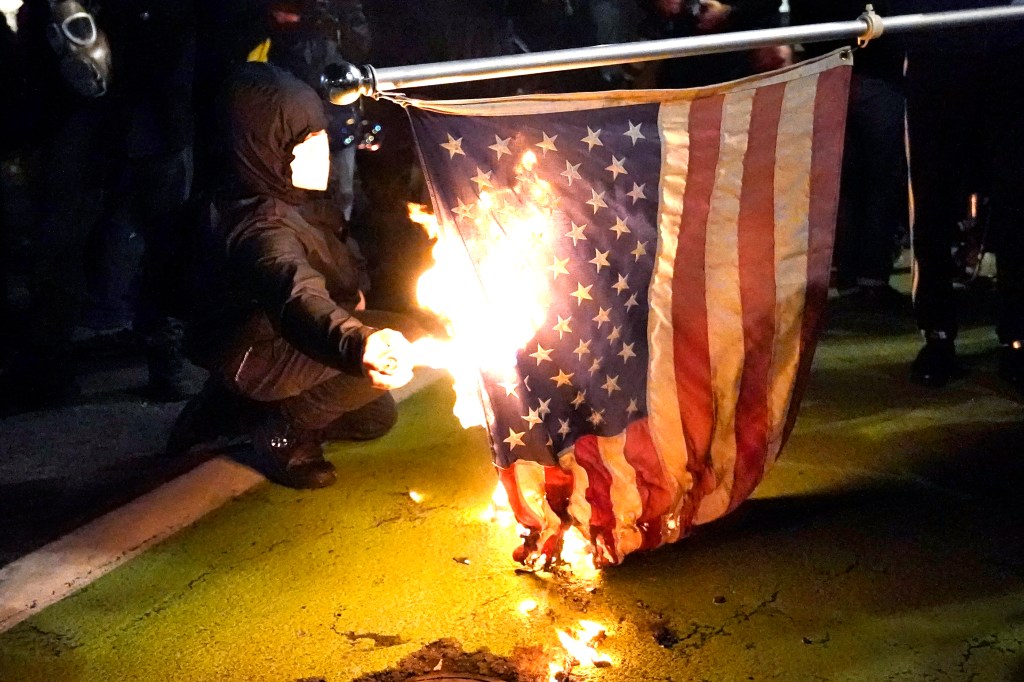 A protester lights an American flag on fire during a demonstration Wednesday, Nov. 4, 2020, in Portland, Oregon.