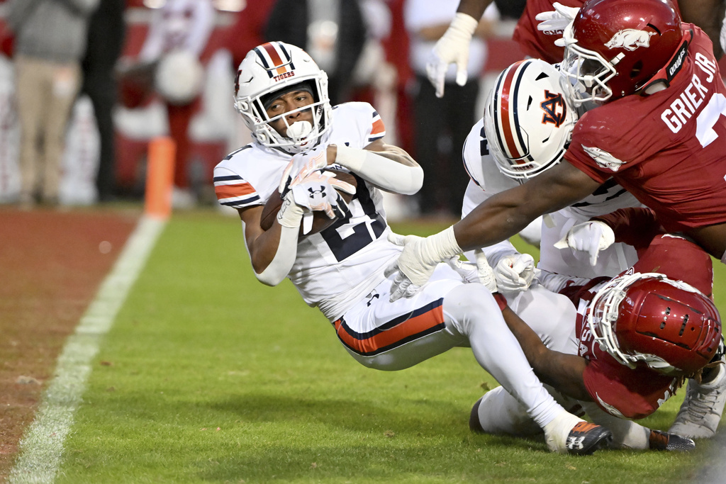 Auburn running back Brian Battie (21) pushes past Arkansas defenders to score a touchdown during the second half of an NCAA college football game Saturday, Nov. 11, 2023, in Fayetteville, Ark. 