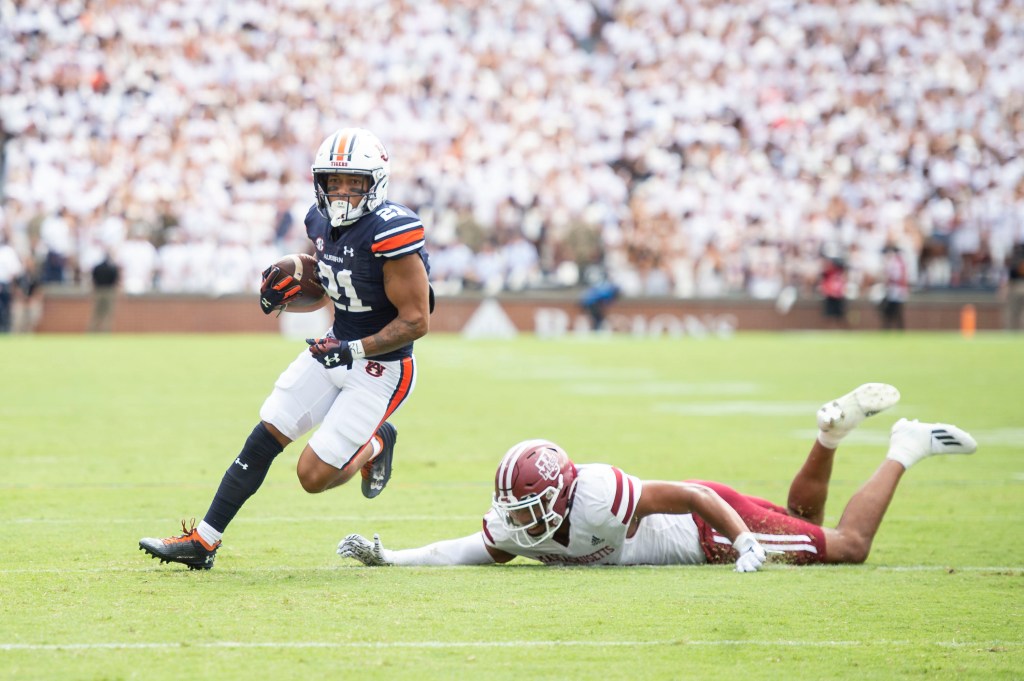 Running back Brian Battie #21 of the Auburn Tigers runs the ball by linebacker Jalen Stewart #23 of the Massachusetts Minutemen