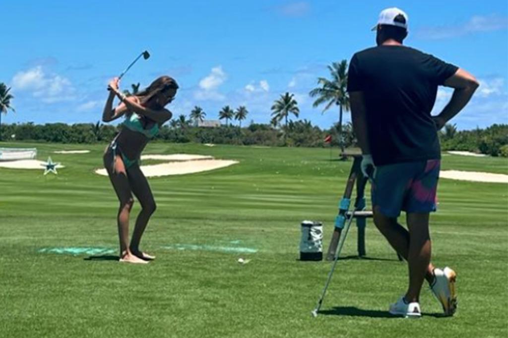 Jena Sims is seen practicing her golf swing as husband Brooks Koepka looks on.