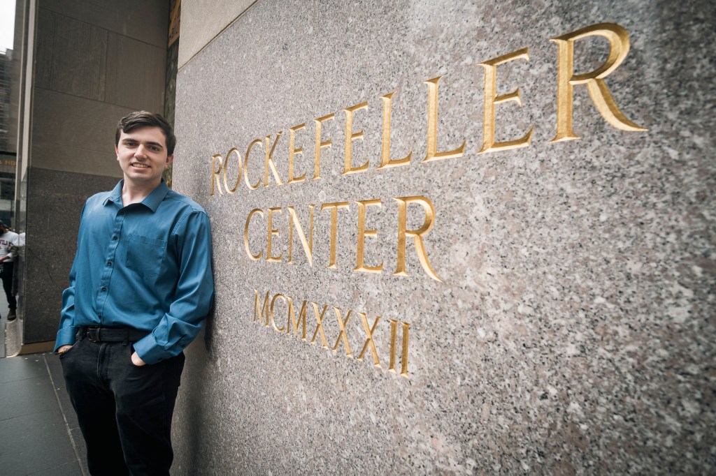 Sky Cabtree, a journalism intern, working at WNBC at 30 Rockefeller Center in Manhattan, New York, standing next to a sign