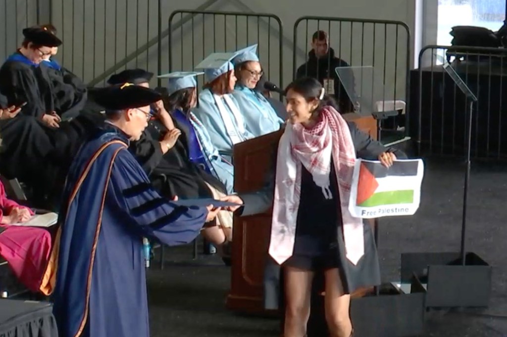 A Keffiyeh-clad Veda Kamra clutches a "Free Palestine" sign as she accepted her diploma. 