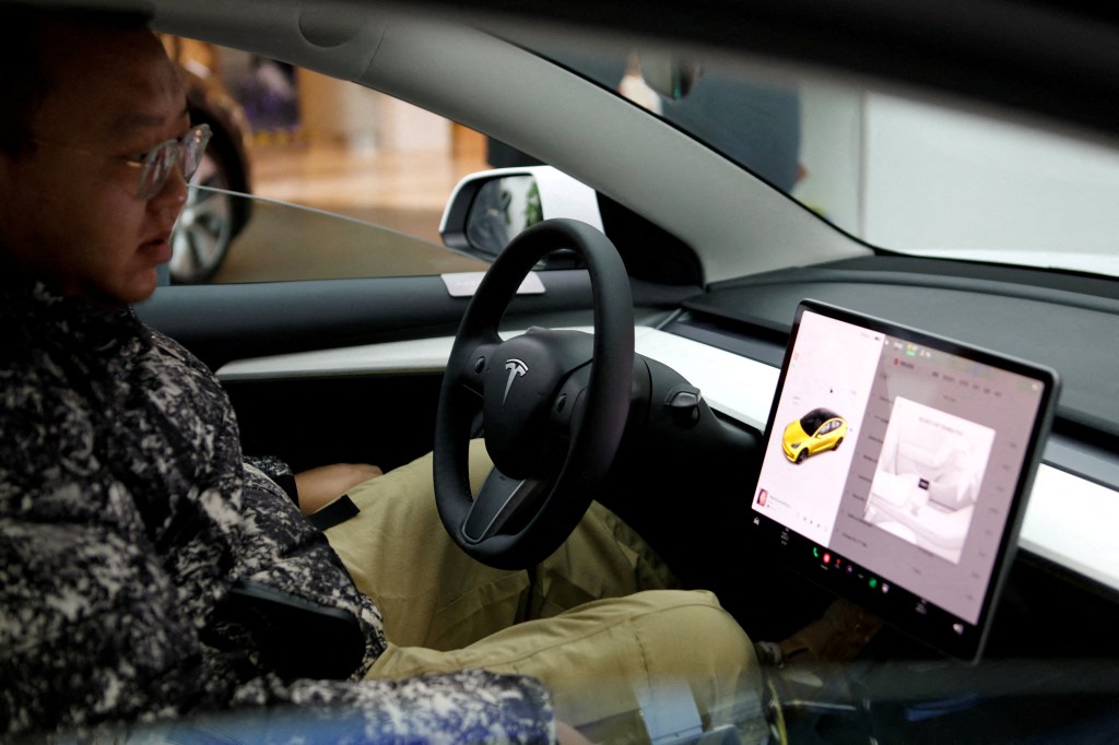 A visitor checks a Tesla Model 3 car at a showroom of the U.S. electric vehicle maker in China.