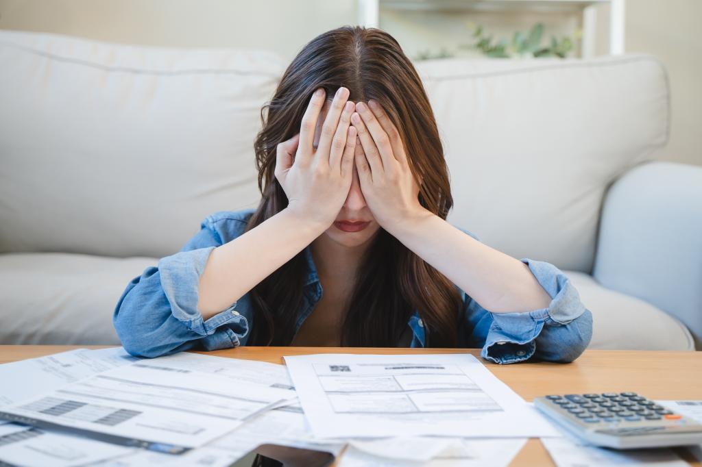 Young Asian woman covering her head with hands, stressed about credit card debts and bills