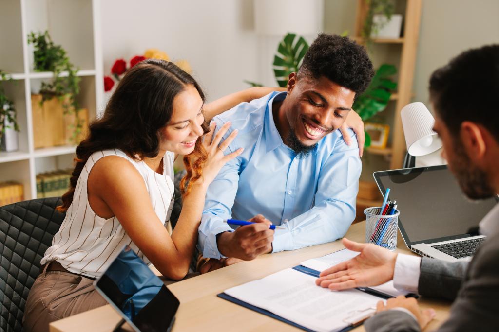 Young Latin American couple signing a contract with an agent in an office setting