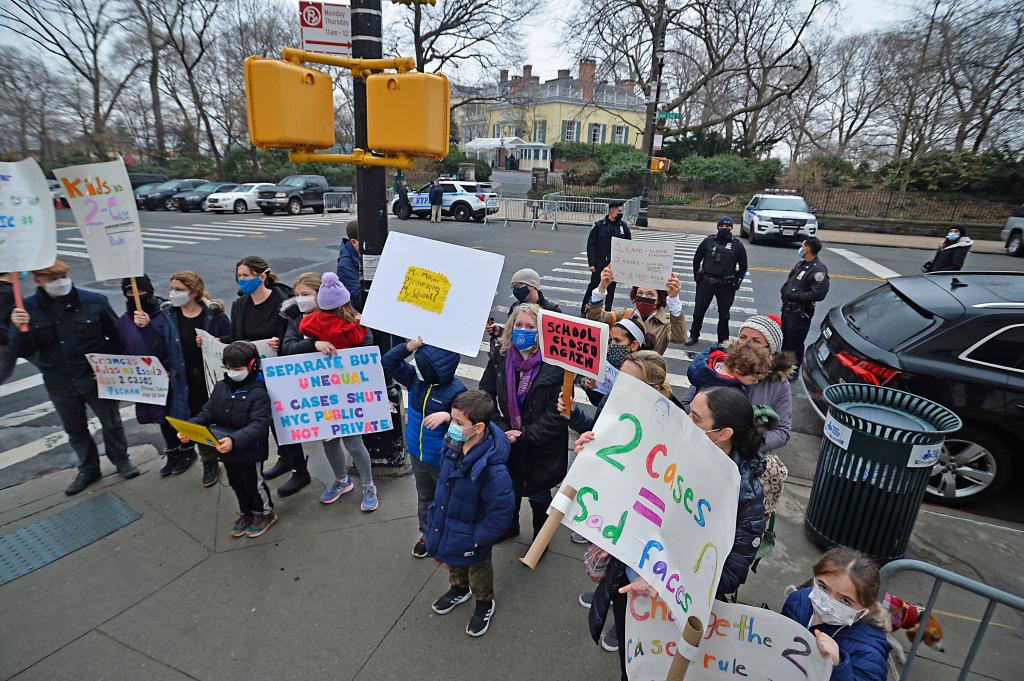 Kids and parents in masks protesting school closures in New York City.