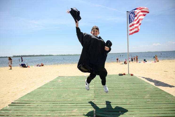 11-year-old Joe Petraro jumping while wearing his cap and gown