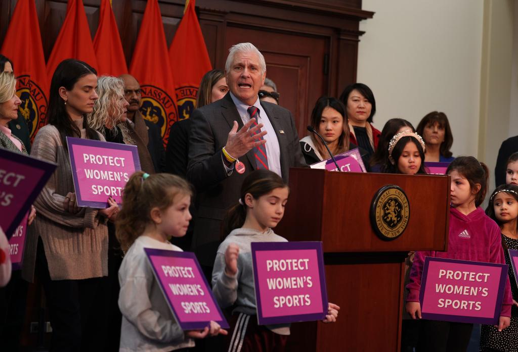 Bruce Blakeman, Nassau County Executive, standing at a podium in front of children at the Theodore Roosevelt Building, announcing a controversial sports policy