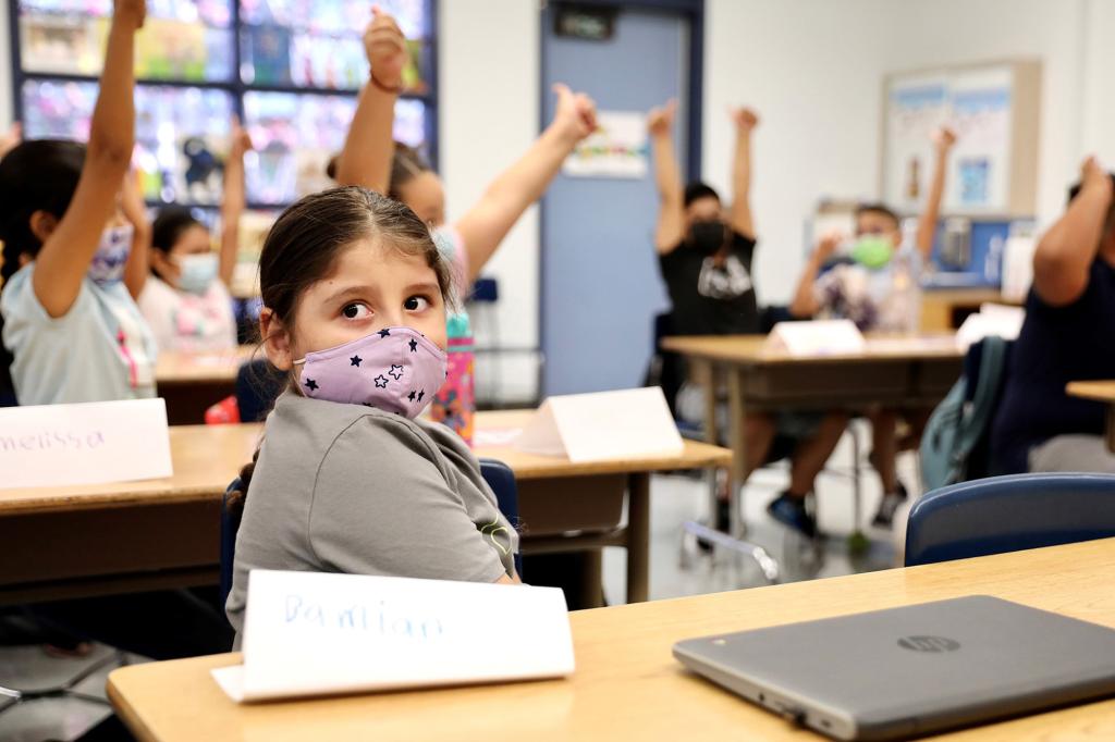 A young girl wearing a pandemic mask in a classroom.