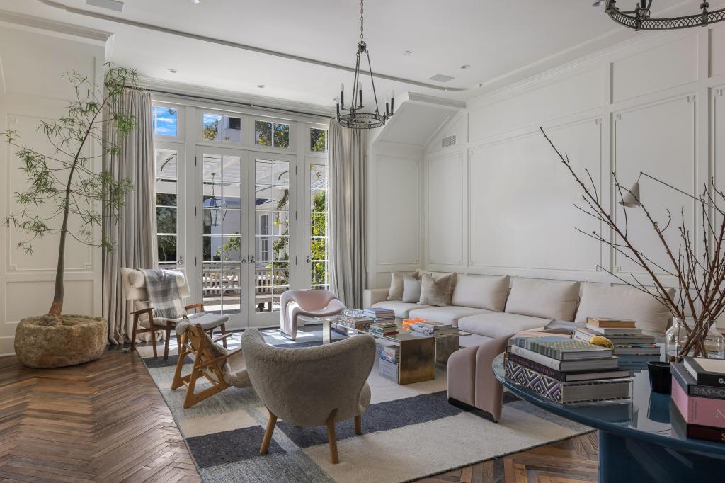 Listing photos show the bright and airy boasts floor to ceiling windows that look out over manicured gardens. 