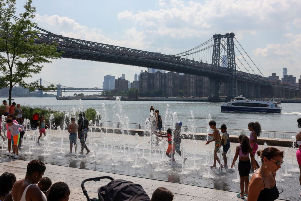 People cool off in a fountain in Domino Park