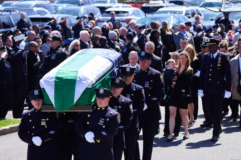 Diller's wife and son at his funeral in Long Island with hundreds of mourners around them.