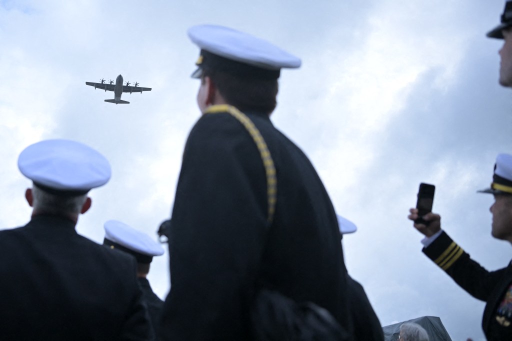 Military plane flying over personnel at the inauguration of a monument for NCDUs and Scouts and Raiders on Omaha Beach, France during 80th D-Day anniversary