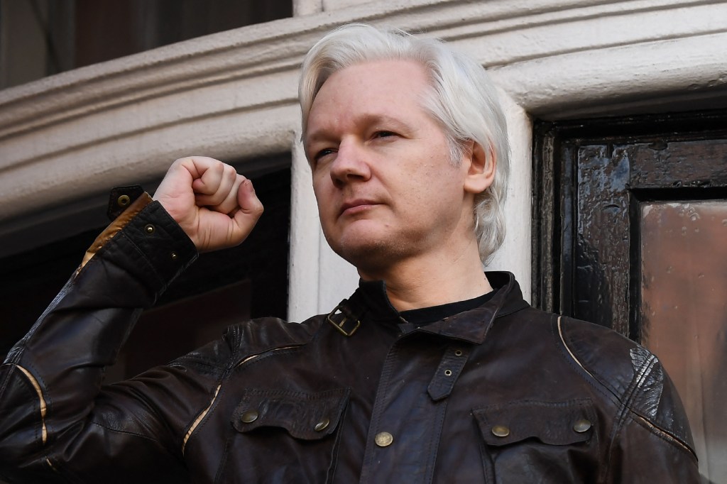 Assange raises his fist prior to addressing the media on the balcony of the Embassy of Ecuador in London on May 19, 2017.