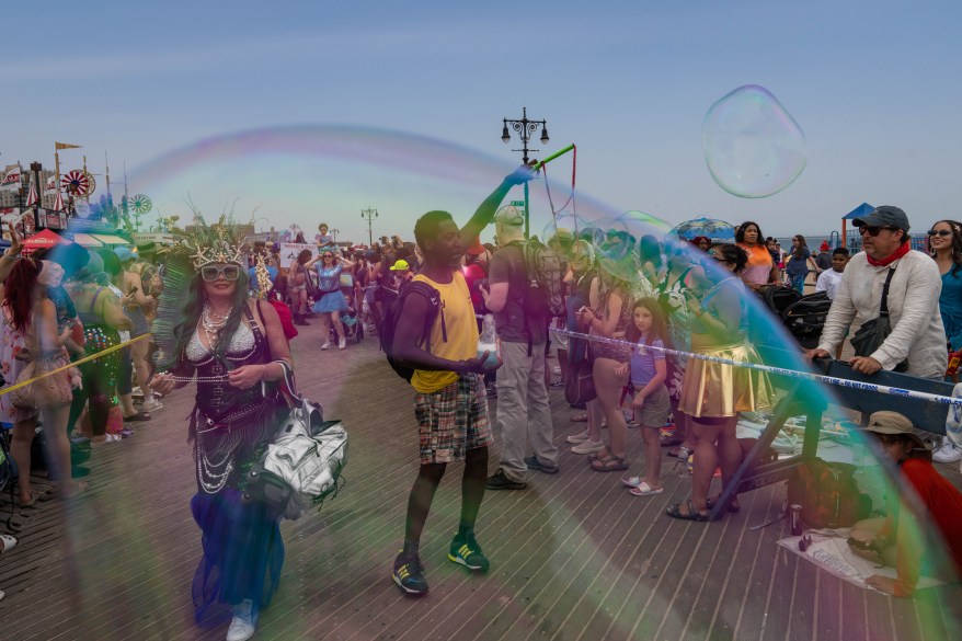 Participants blow bubbles as they walk the boardwalk during the Annual Coney Island Mermaid Parade on June 22, 2024