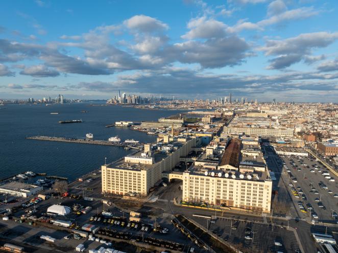 Exterior view of the Brooklyn Army Terminal, New York, a large military supply base from World War II, with city skyline and body of water in the background.