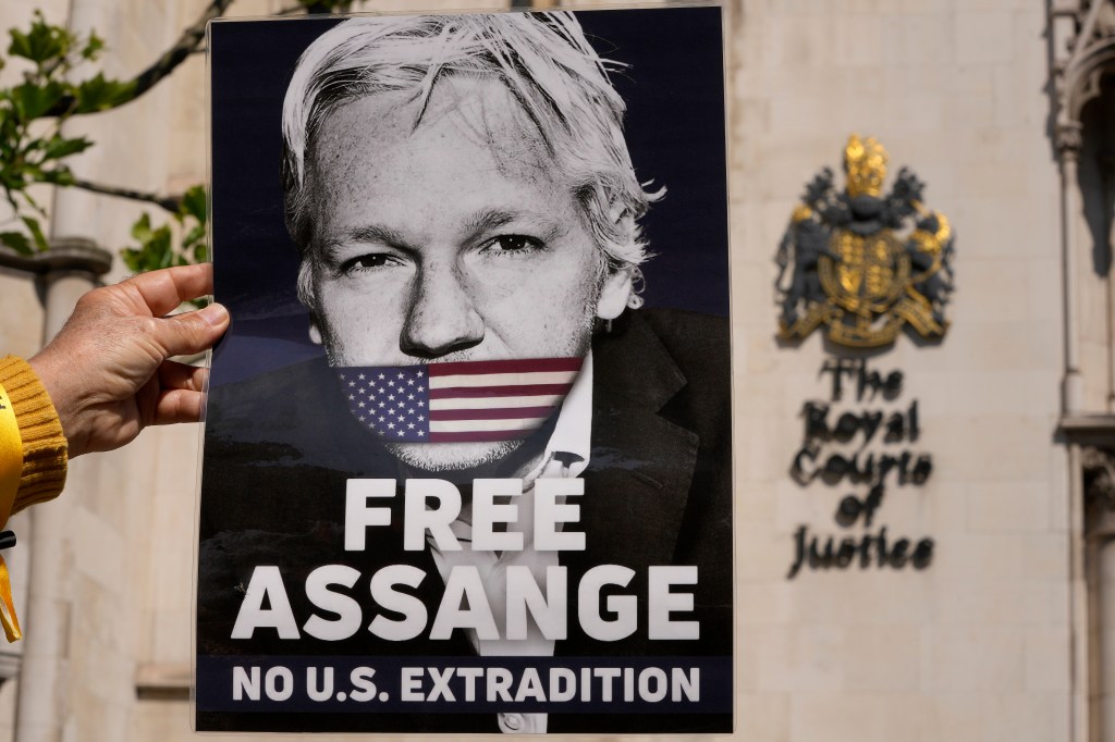 A protester holds a poster of WikiLeaks founder Julian Assange outside the High Court in London, Monday, May 20, 2024. 