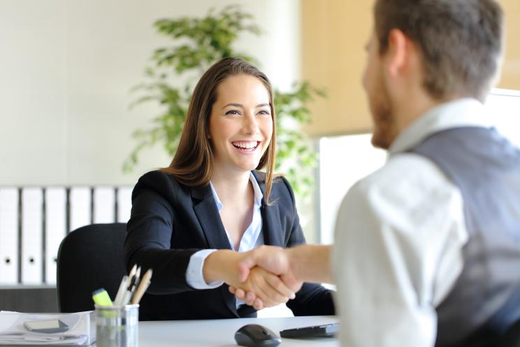 Businesspeople, a man and a woman, handshaking after a deal or interview