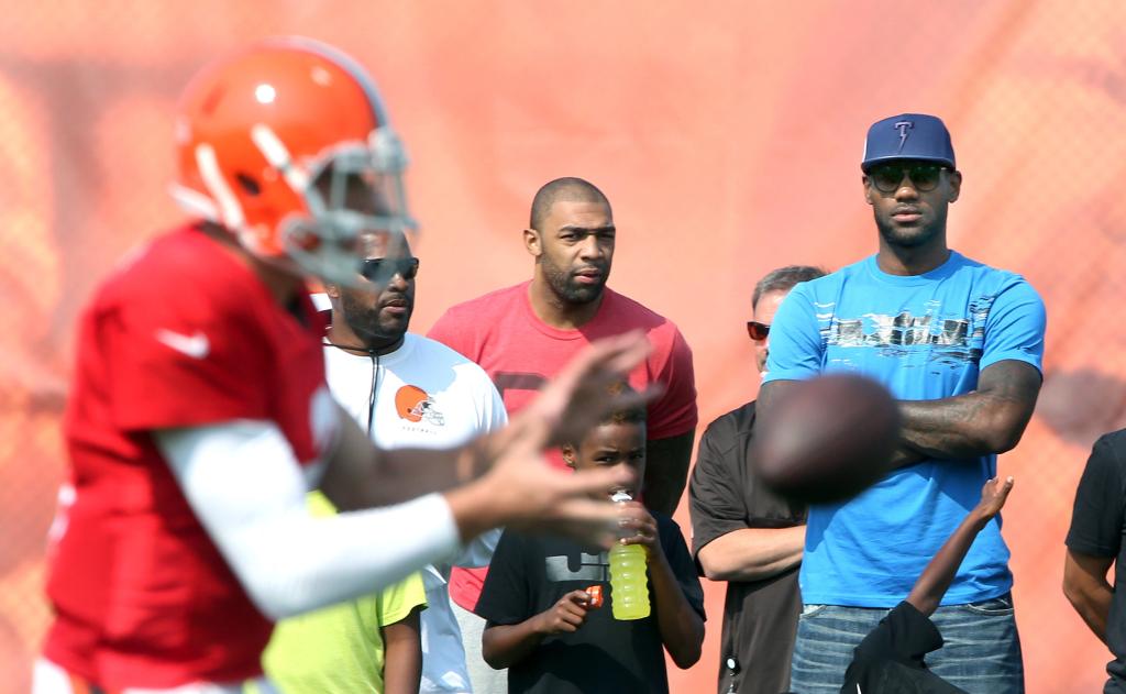 Cleveland Cavaliers' LeBron James, right, watches Cleveland Browns quarterback Johnny Manziel at the Browns training camp in Berea, Ohio, Thursday, Aug. 7, 2014. 