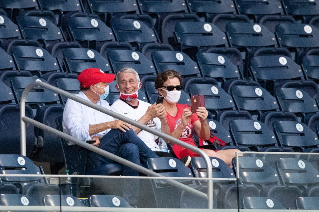 Anthony Fauci with a mask on his chin at a baseball game.