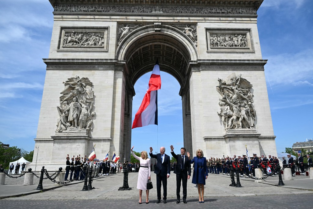 The Bidens and Macrons wave to the crowd during a welcome ceremony at the Arc de Triomphe in Paris.