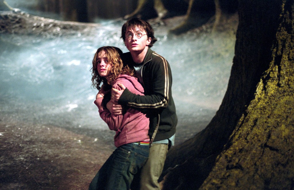 Harry and Hermione hugging and looking worried, hiding behind a tree, in "Harry Potter and the Prisoner of Azkaban." 