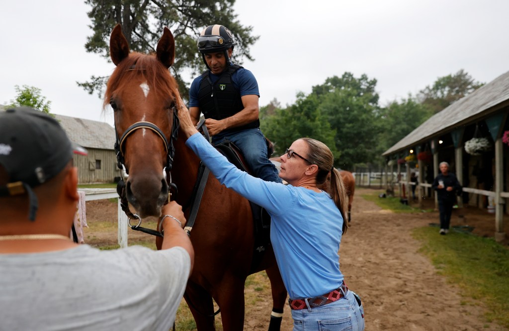 Jena Antonucci pets one of her horses as after she helped her exercise rider onto a horse at her barn at Saratoga Race Course.