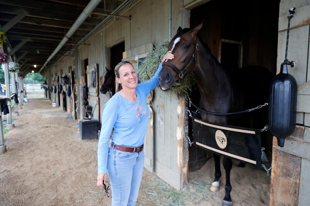 Jena Antonucci poses for a picture next to her horse Do Gooder at her barn at Saratoga Race Course in Saratoga Springs, New York.