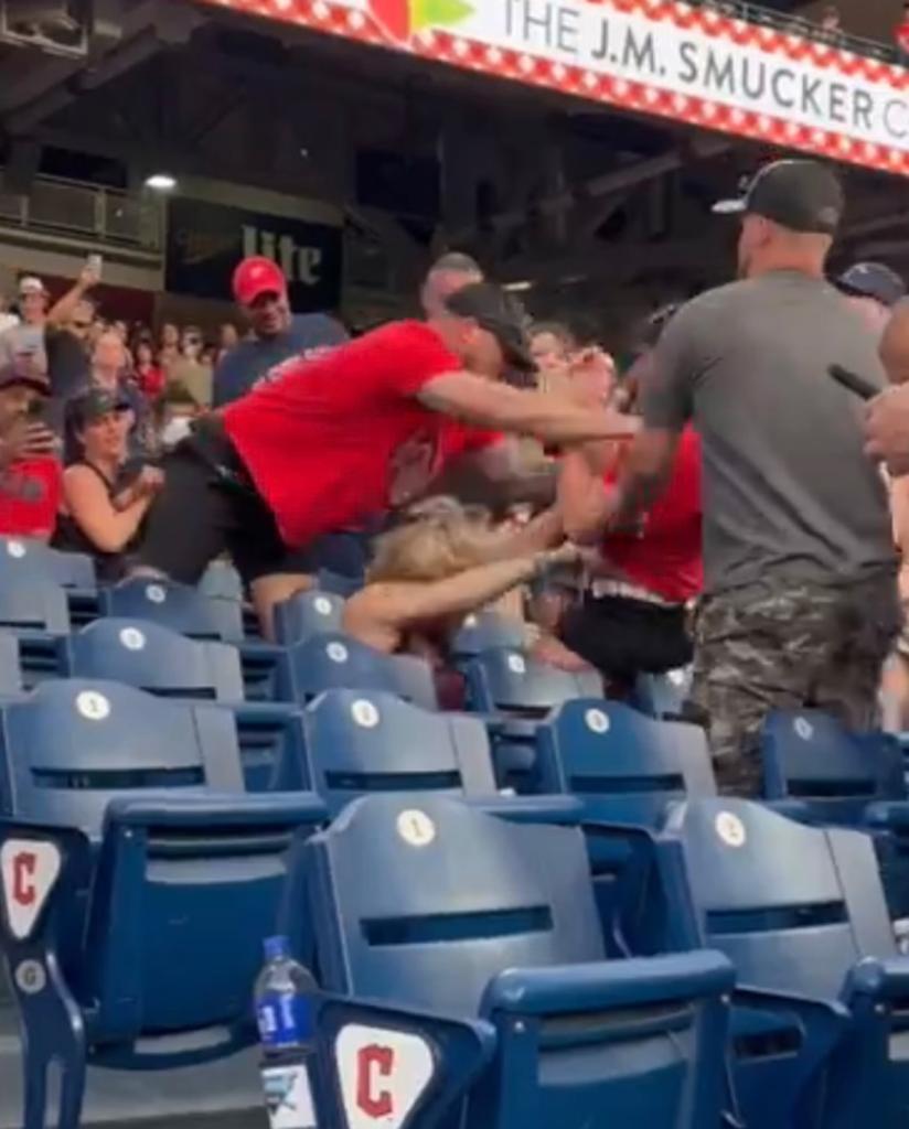 Brawl breaking out in the stands during a Cleveland Guardians game against the Toronto Blue Jays, featuring a man holding a woman in front of a crowd.