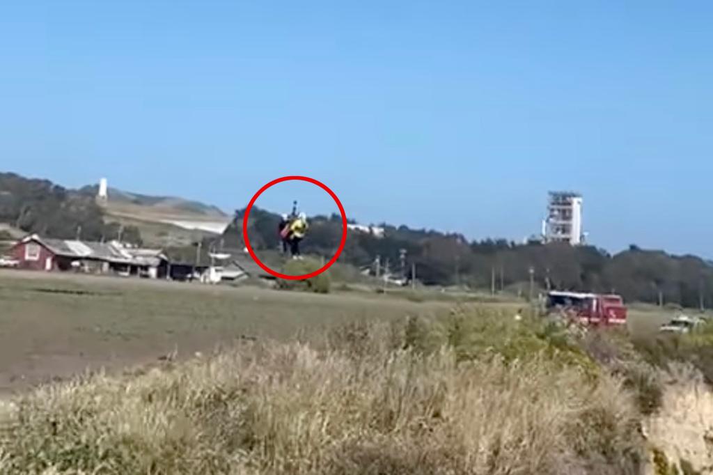 A helicopter flying over a beach to rescue a stranded kite surfer who spelled out 'HELP' with rocks on the beach