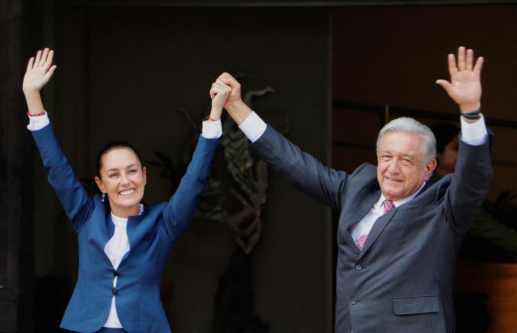 Claudia Sheinbaum holds hands in victory with Andres Manuel Lopez Obrador.